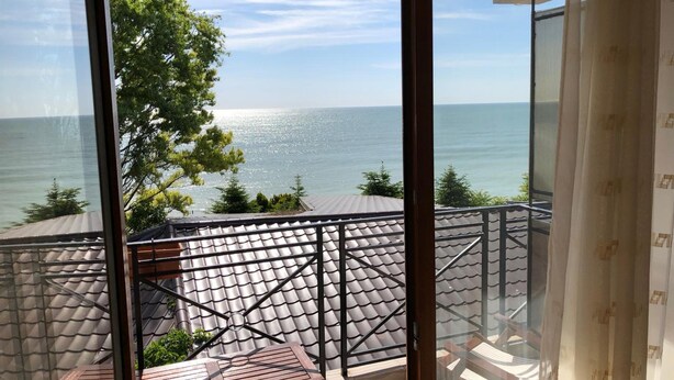 A balcony with a view of the sea, a tiled roof, and a wooden table. - Pensiunea Trident (Hateg)