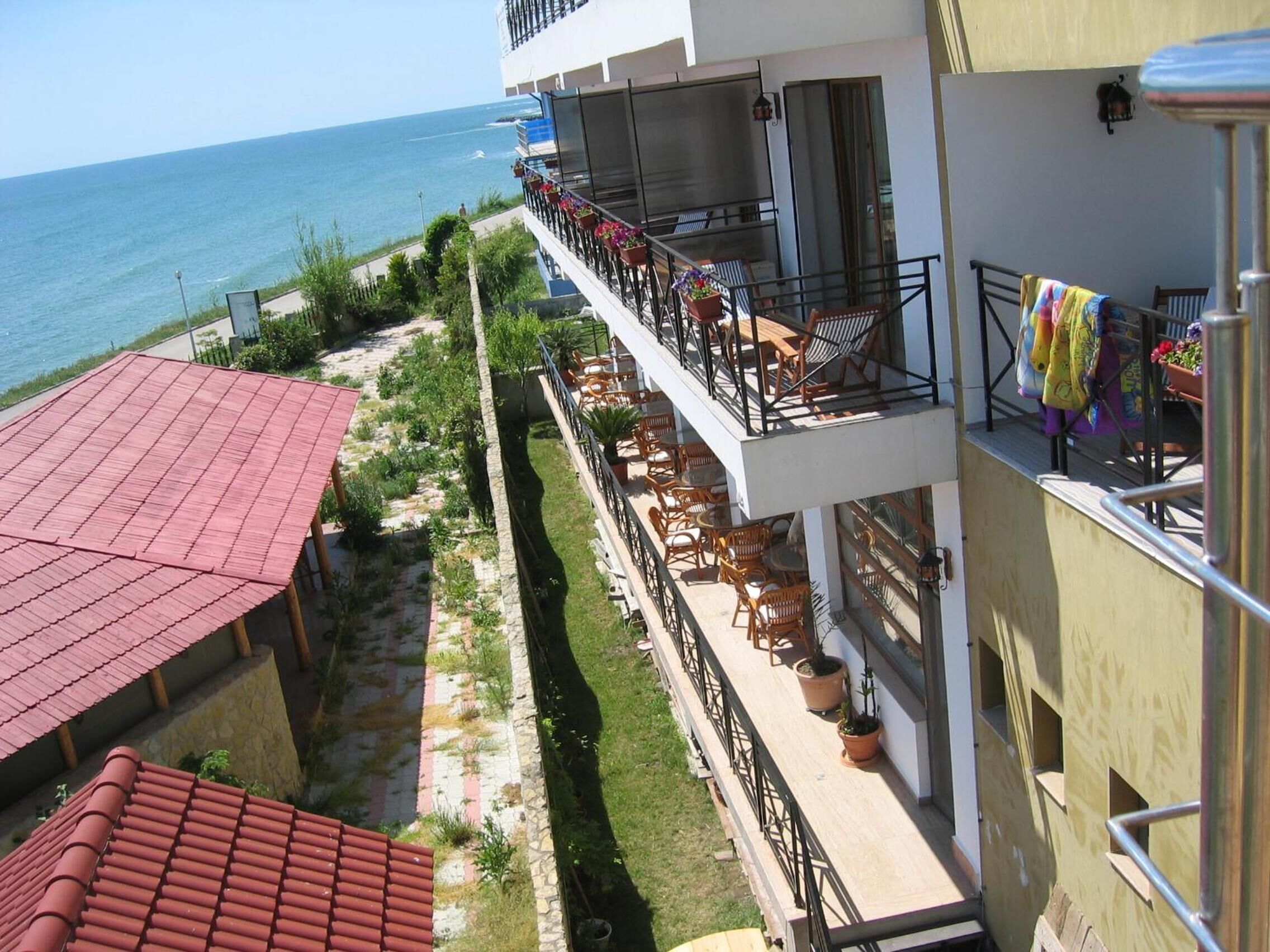 Ein Hotel mit Balkon und Meerblick, inklusive Außenmöbeln und Pflanzkübeln.