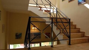 A staircase with a metal railing, wooden steps, and wall-mounted pictures. - Pensiunea Trident (Hateg)