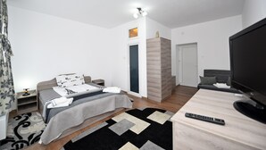 A modern bedroom with a bed, bedside table, TV, and a wardrobe. - Pensiunea Trident (Hateg)