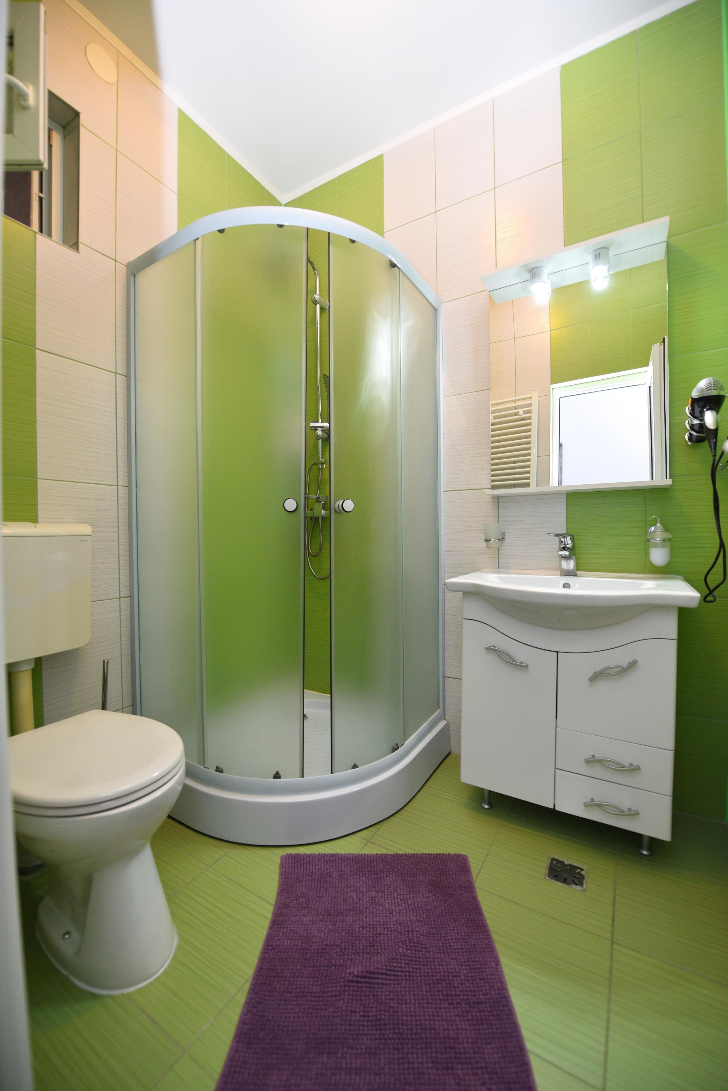 A bathroom with a toilet, a shower enclosure, a sink, and a mirror.