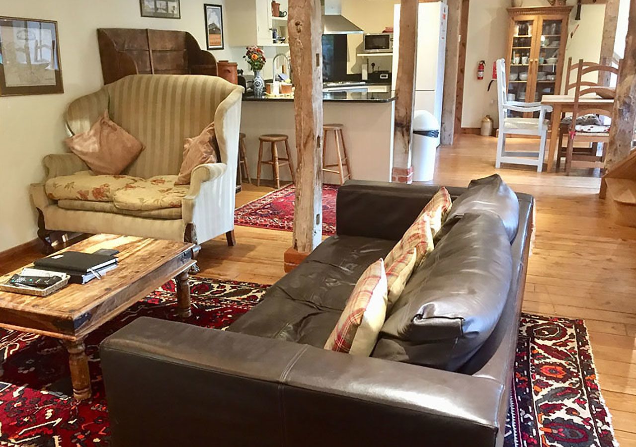 Ein Wohnzimmer mit einer Couch, einem Sessel, einem Couchtisch und einem Teppich.
