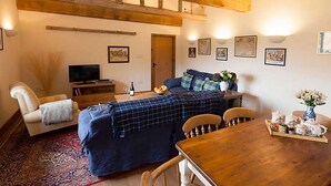 Una sala de estar acogedora con un sofá, un televisor, una mesa de comedor de madera y una mesa de centro.