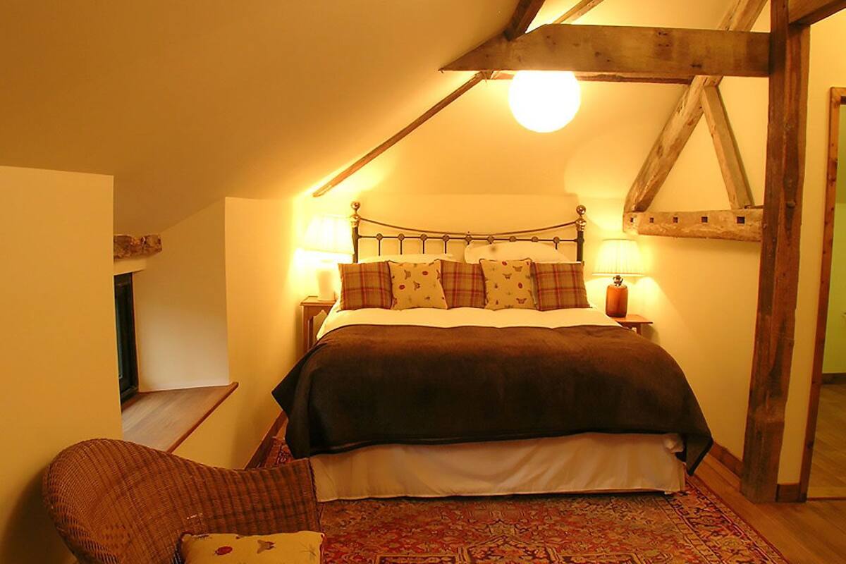 Une chambre confortable avec un lit, une chaise et une lampe.