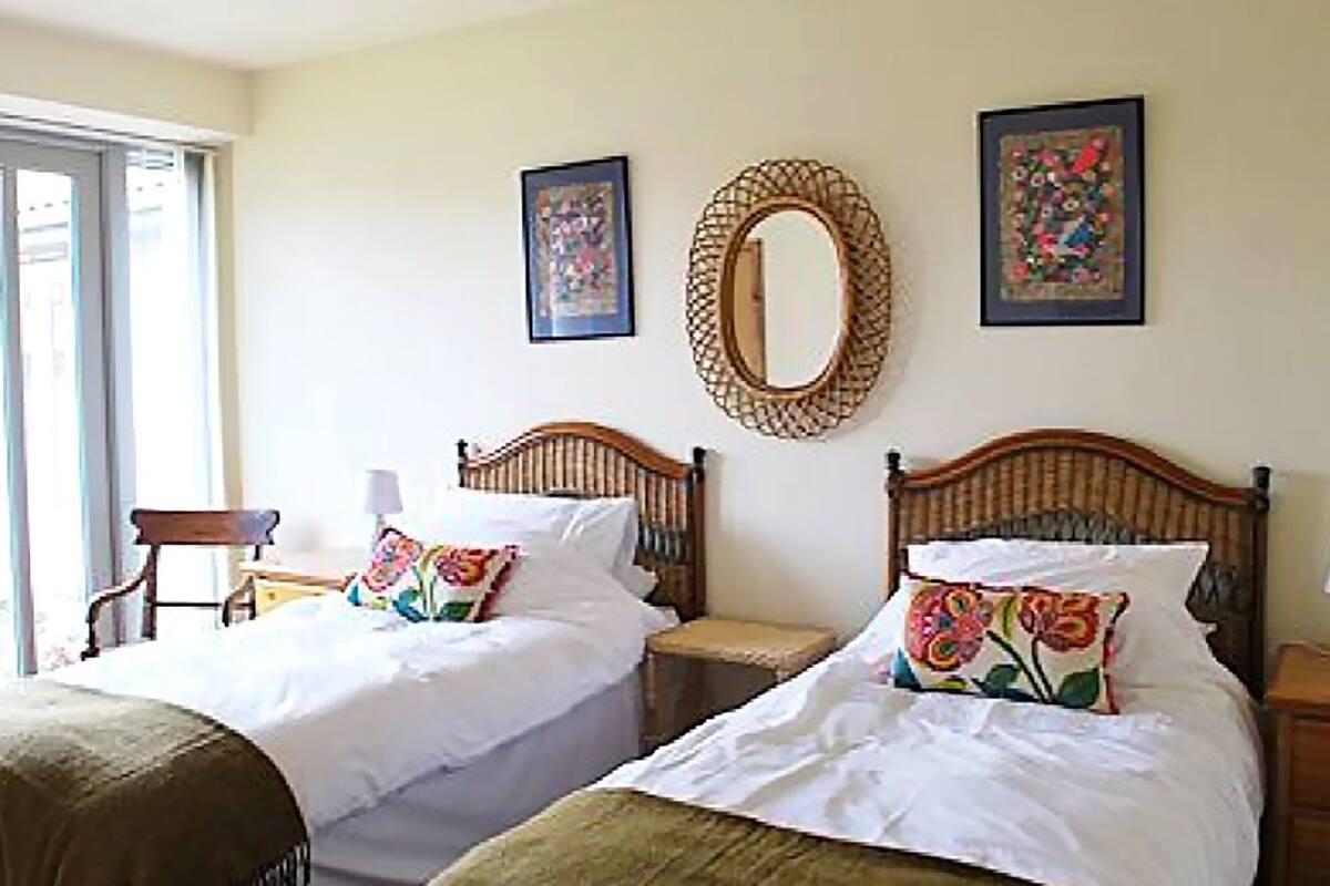 Une chambre d’hôtel avec deux lits en bois, un grand miroir et deux œuvres d’art encadrées accrochées au mur.