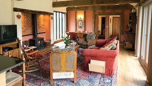 Un salón acogedor con chimenea, vigas de madera, un televisor y un sofá rojo.