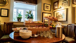 A breakfast buffet with various food items, a coffee pot, and a window with plants.