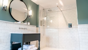A bathroom with a white-tiled shower, a dark wooden vanity with a mirror, and a white bathtub.