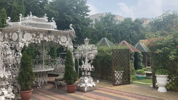A garden with ornate metalwork, potted plants, and a gazebo. - Inn on Zhytomyrska (Kyiv)