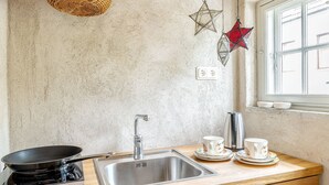 Een keuken met houten kastjes, een roestvrijstalen spoelbak, een fornuis en decoratieve elementen.