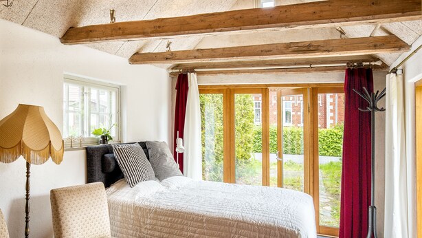 Een slaapkamer met een groot bed, een stoel, een lamp en uitzicht.