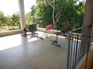 A balcony with a concrete floor, a metal railing, and a view of trees and greenery. - Border (Habarana)