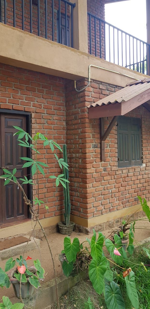 A brick building with a balcony, a door, and potted plants.
