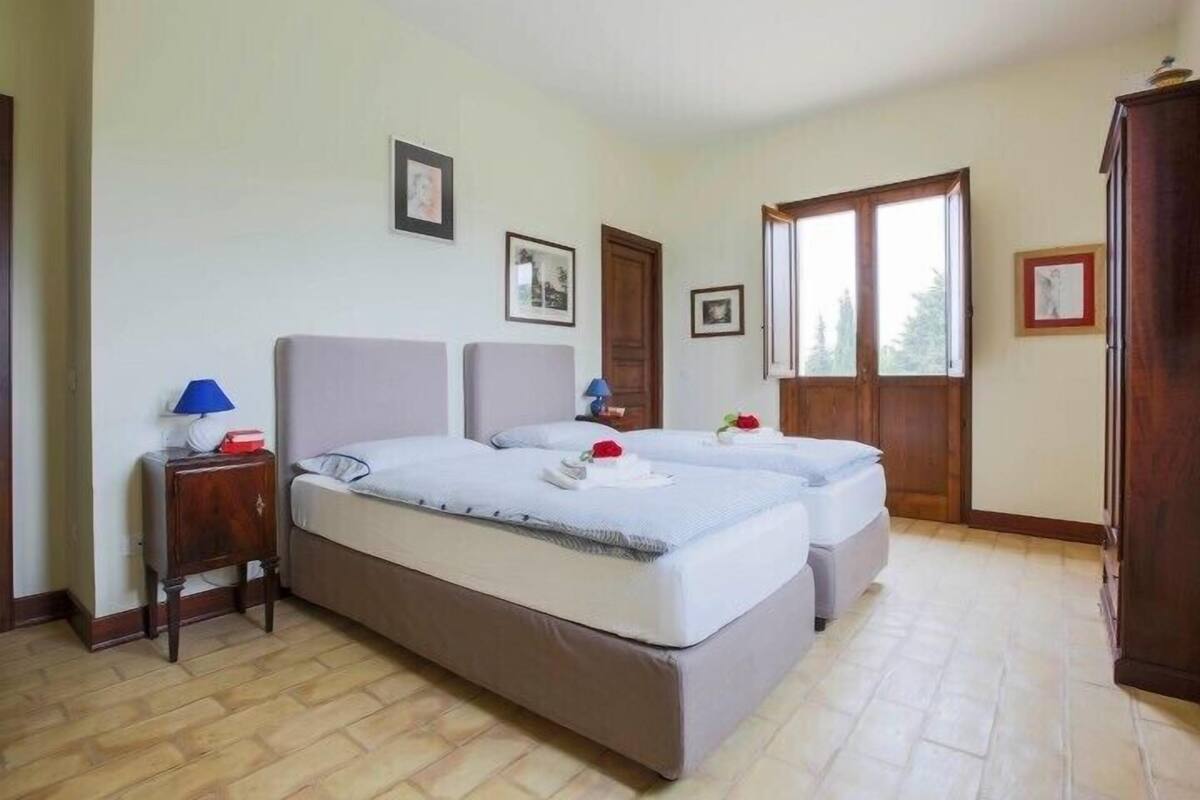 Ein Hotelzimmer mit zwei Betten, einem Holzschrank und einem Fenster mit Blick.