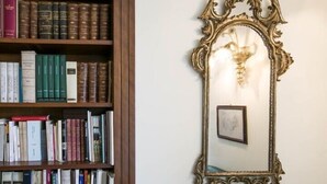 Ein Bücherregal voller Bücher und ein aufwändig gestalteter Wandspiegel mit Leuchtelement.