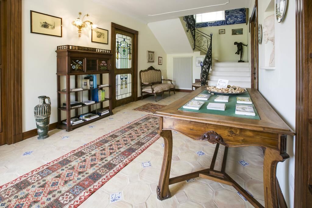 Una habitación con un escritorio de madera, una alfombra estampada, una estantería y una escalera.