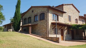 Una casa de piedra con techo inclinado, varias ventanas y un camino de entrada pavimentado.