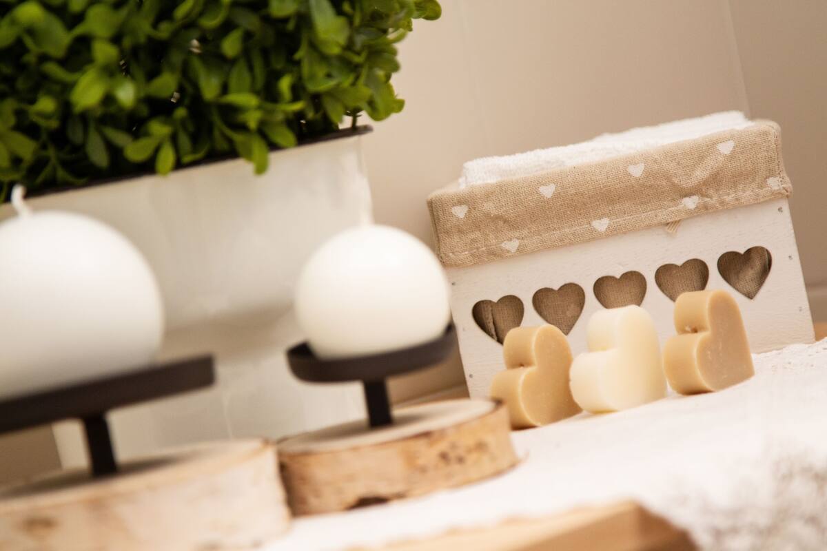 A wooden shelf with decorative items including a potted plant, candles, and soap bars.