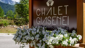 A sign for Chalet Gisenei with a mountainous backdrop and a flower display.