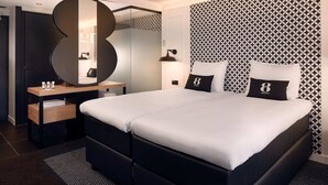 A modern hotel room with a large bed, a bedside table, a mirror, and a patterned wall. - Gr8 Hotel Bodegraven (Bodegraven)