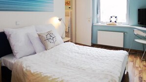 A bedroom with a bed, a desk, a window, and a painting on the wall. - Hotel Monte Christo (Cologne)
