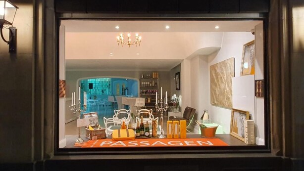 A hotel interior with a reception desk labeled "PASSAGEN," a chandelier, and a view into a dining area with blue-tiled walls and white furniture. - Hotel Monte Christo (Cologne)