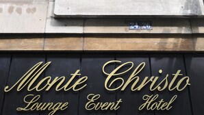A building facade with a stone lion sculpture, a window, and the text "Monte Cristo Lounge Event Hotel". - Hotel Monte Christo (Cologne)
