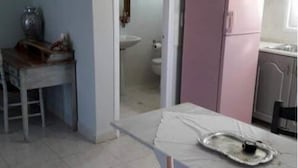 A kitchen with a dining table, chairs, a refrigerator, and cabinets. - Brezza Apartment D (Karpathos)