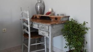 A small, compact room with a wooden desk and a chair, a potted plant, and a decorative vase. - Brezza Apartment D (Karpathos)