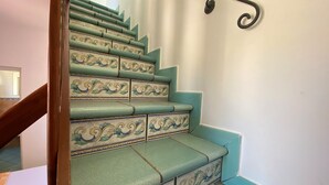 A staircase with ornate, patterned steps and a wooden handrail. - Terrazze XXV Novembre (Cefalù)