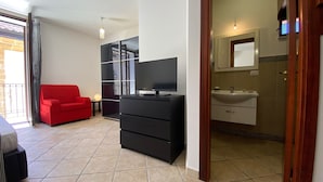 A modern living room with a red sofa, a black entertainment unit, and a television. - Terrazze XXV Novembre (Cefalù)