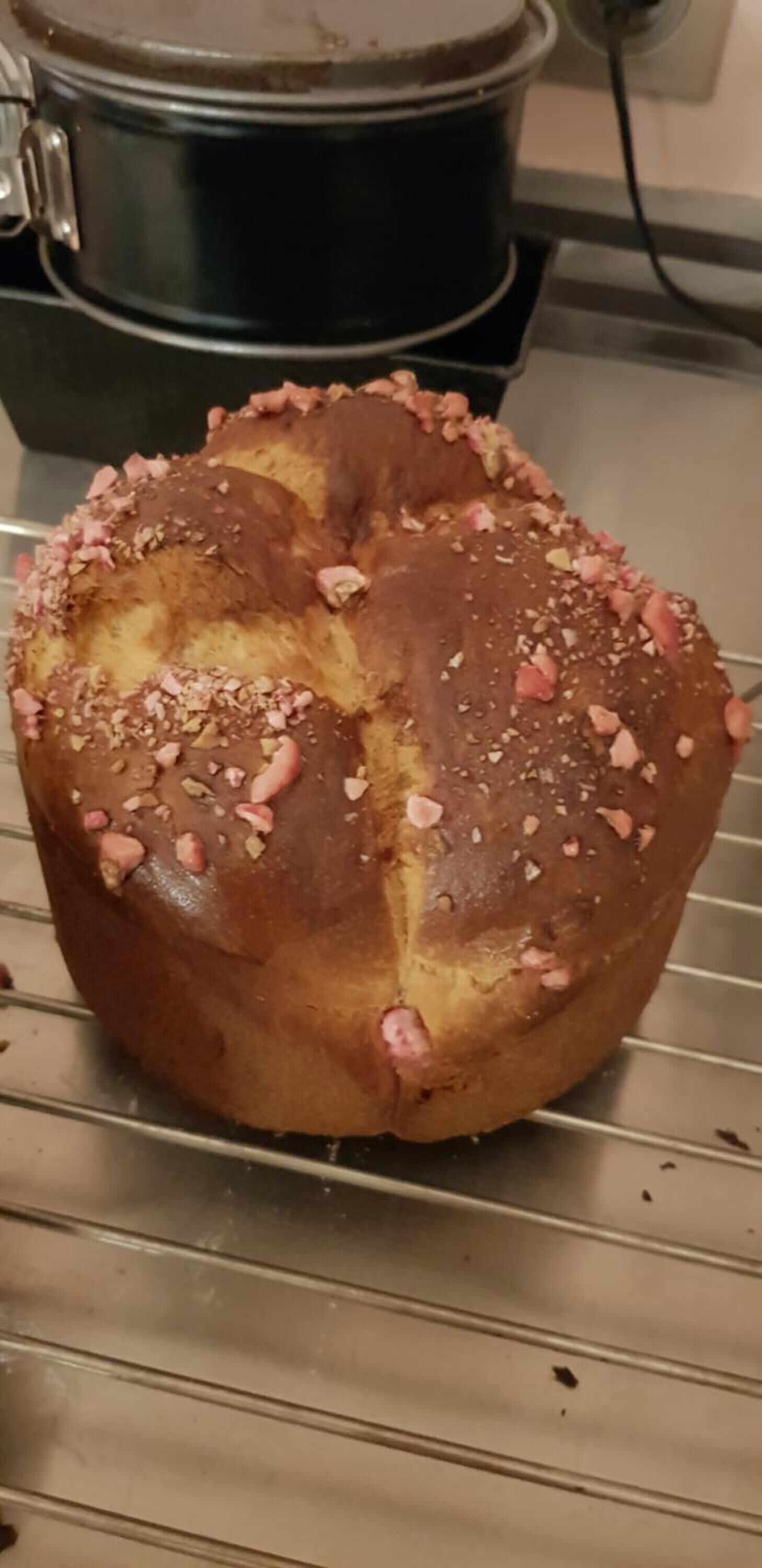 A loaf of bread with pink and white toppings on a metal rack.