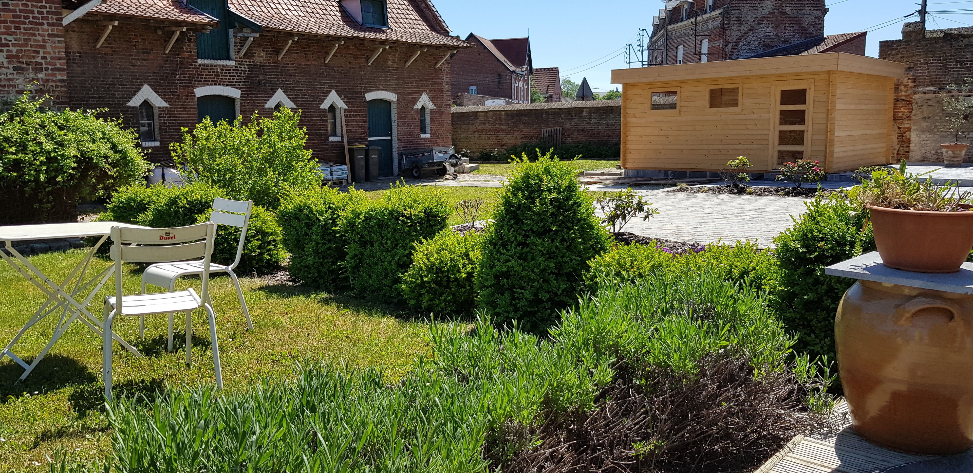 A courtyard with a brick building, a wooden structure, and a white chair.