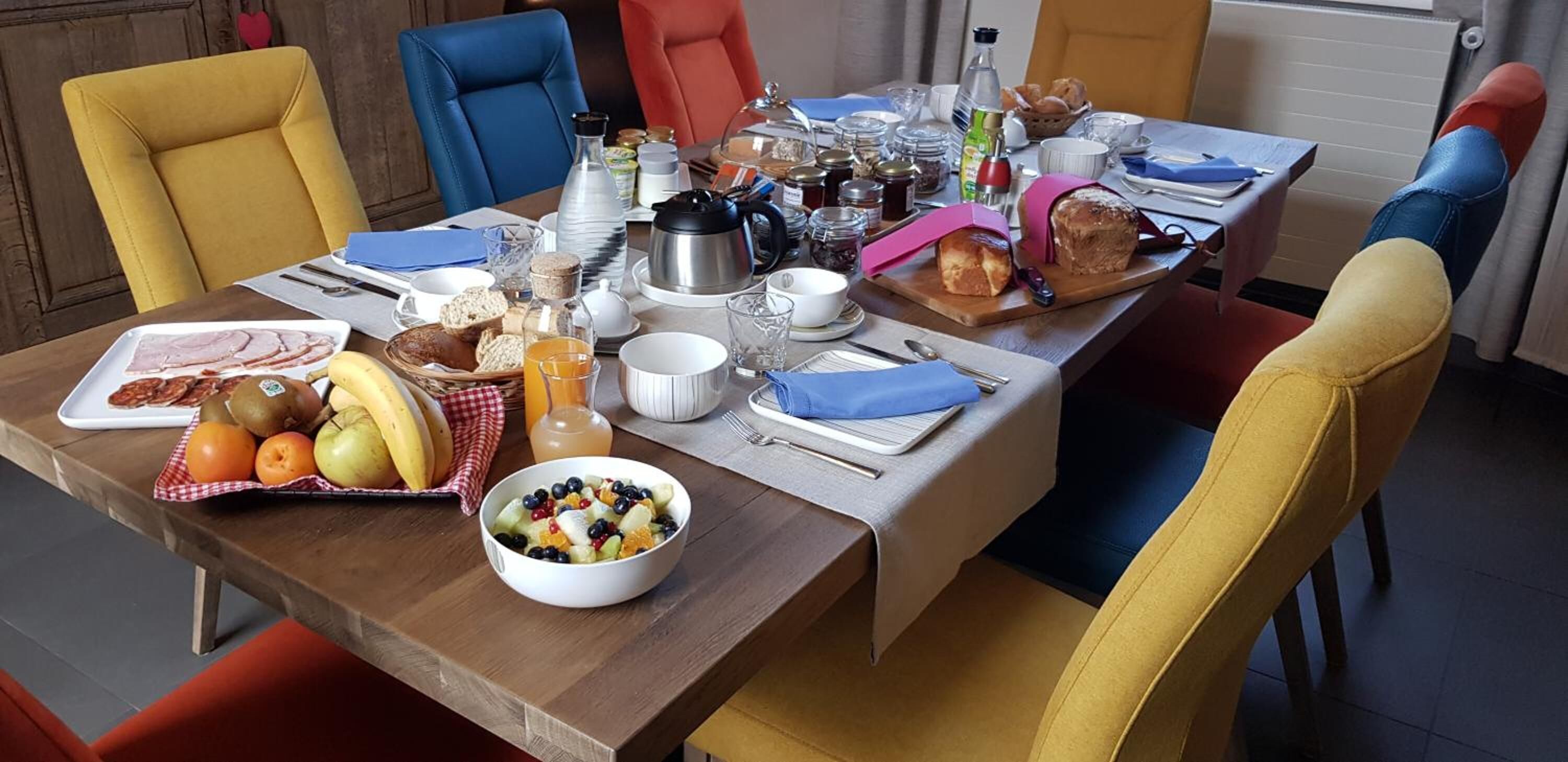 Una mesa de desayuno lista, con diversas opciones como frutas, pan y bebidas.