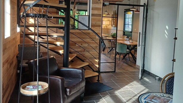 Un interior moderno con una escalera espiral, paredes de madera y un comedor con una mesa redonda y sillas.