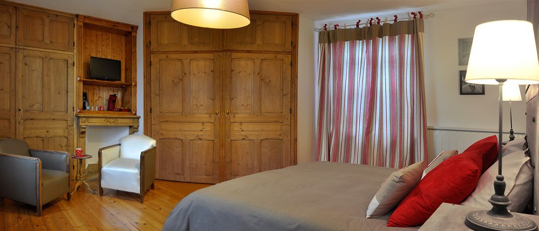 Een slaapkamer met een bed, een stoel, een bureau, een televisie en een kledingkast.