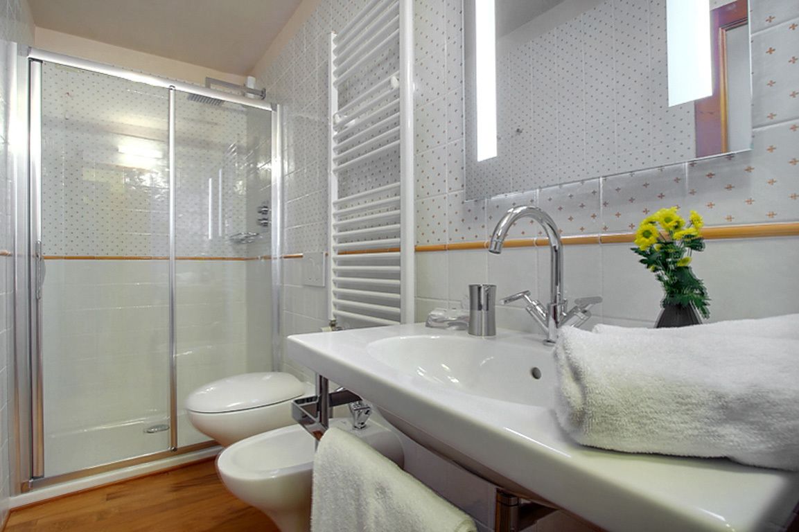A bathroom with a glass shower enclosure, a white sink with a mirror, and a white toilet.