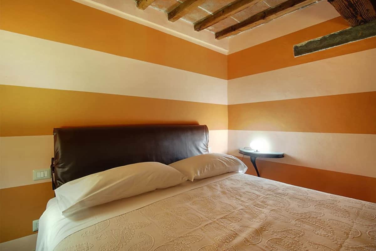 Une chambre avec un lit, une table de chevet et une lampe.