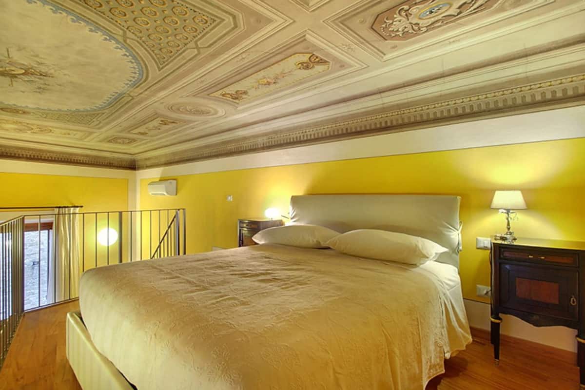Une chambre à coucher avec un grand lit, une table de chevet et un plafond décoratif.