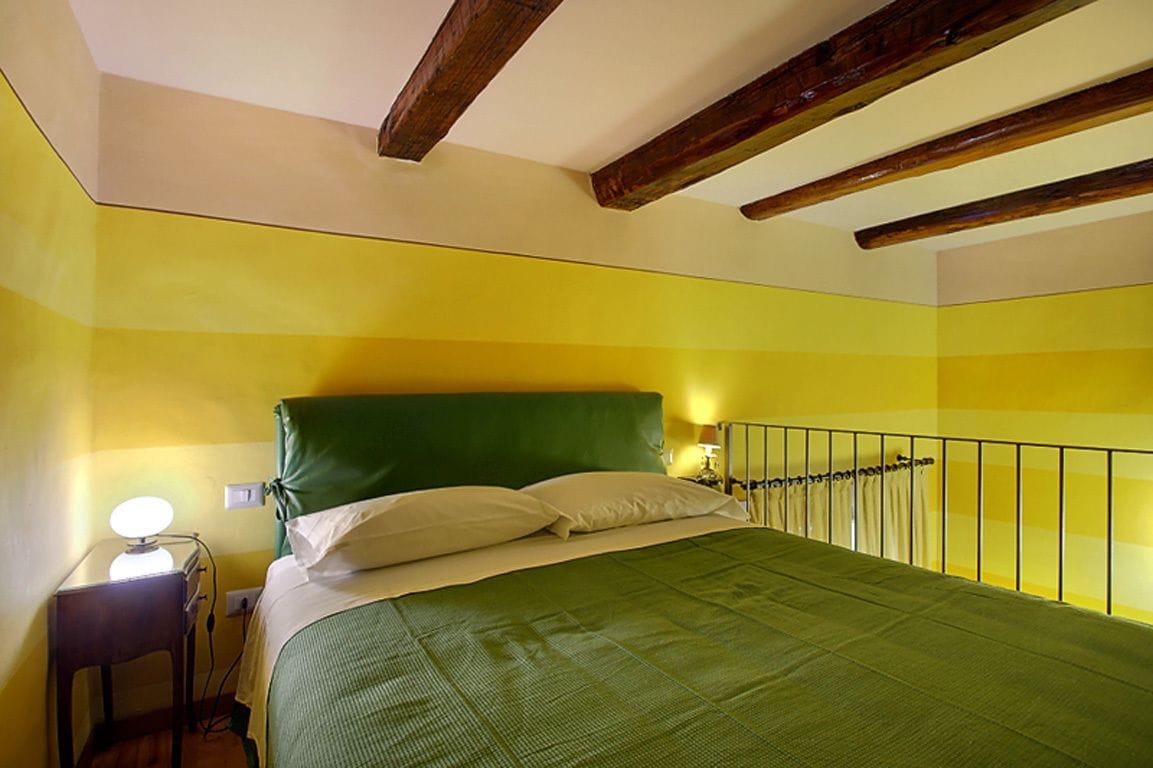 A room with a bed, a bedside table with a lamp, and a railing along the window.