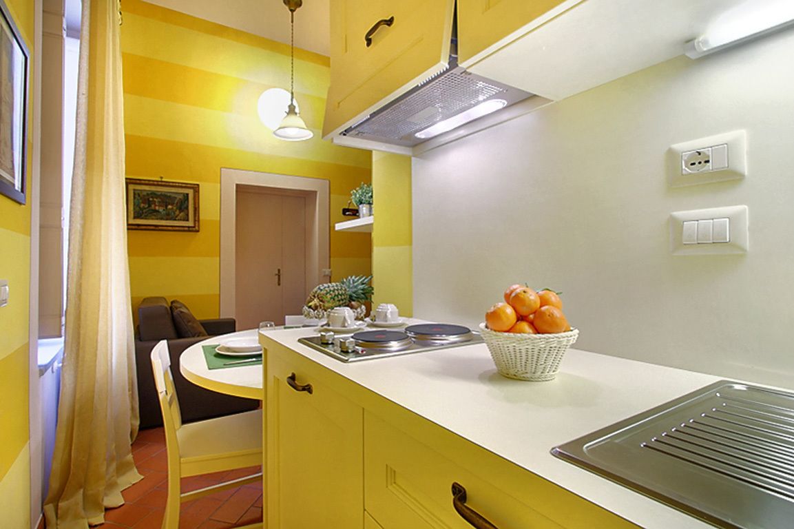 A compact kitchen with a white countertop, a sink, and a fruit bowl.