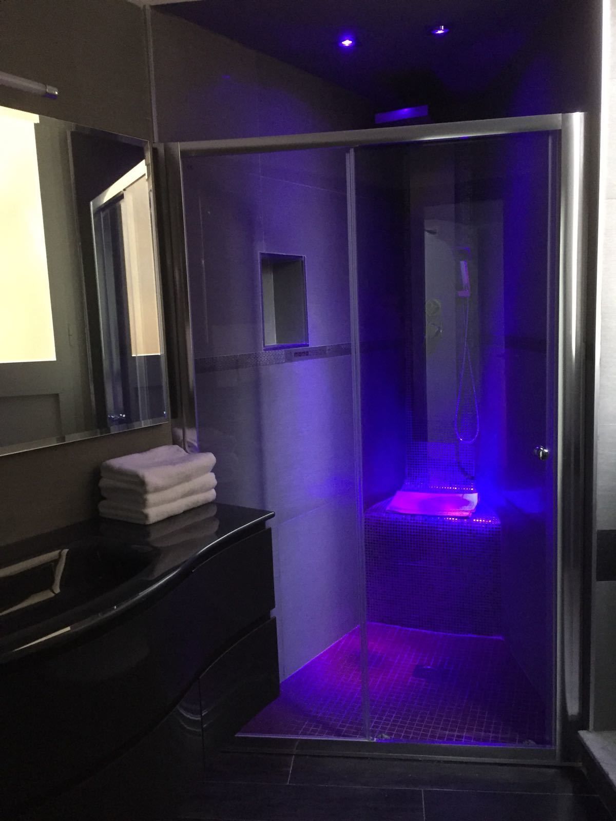 A modern bathroom with a glass-enclosed shower, a black vanity, and a mirror.