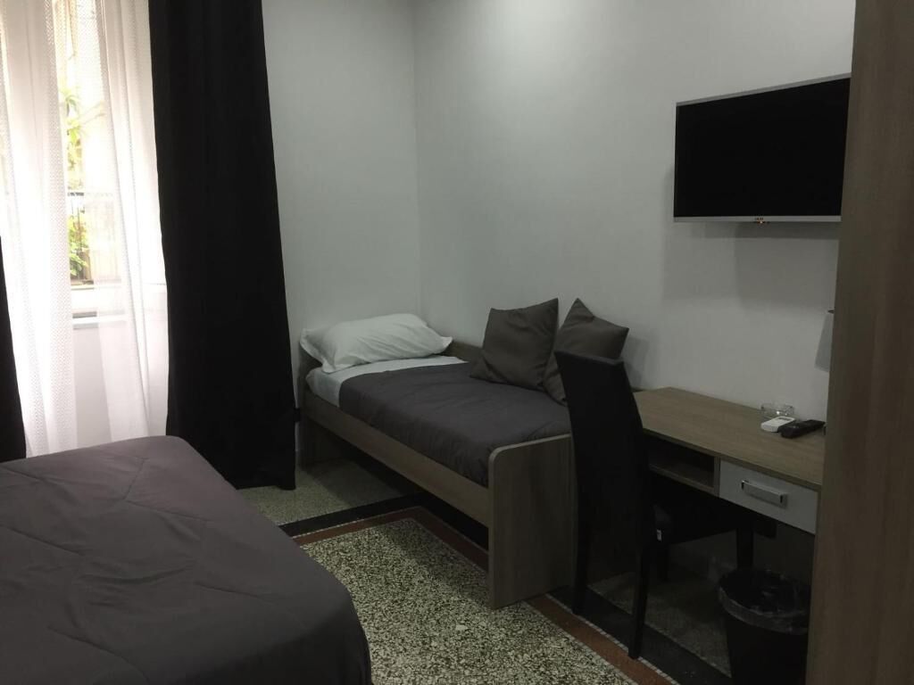 A small, modern room with a bed, a desk, and a TV.
