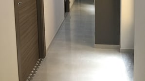 A hallway with a wooden door on the left, a light fixture on the right, and a tiled floor. - MB95 Mezzocannone Luxurious B&B (Naples)