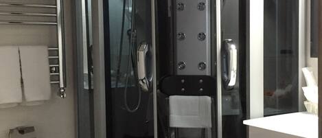 A modern bathroom with a glass-enclosed shower, a white sink, and a towel rack.