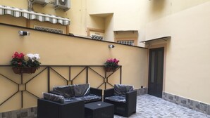 A courtyard with outdoor furniture, two flower planters, and a tiled floor. - MB95 Mezzocannone Luxurious B&B (Naples)