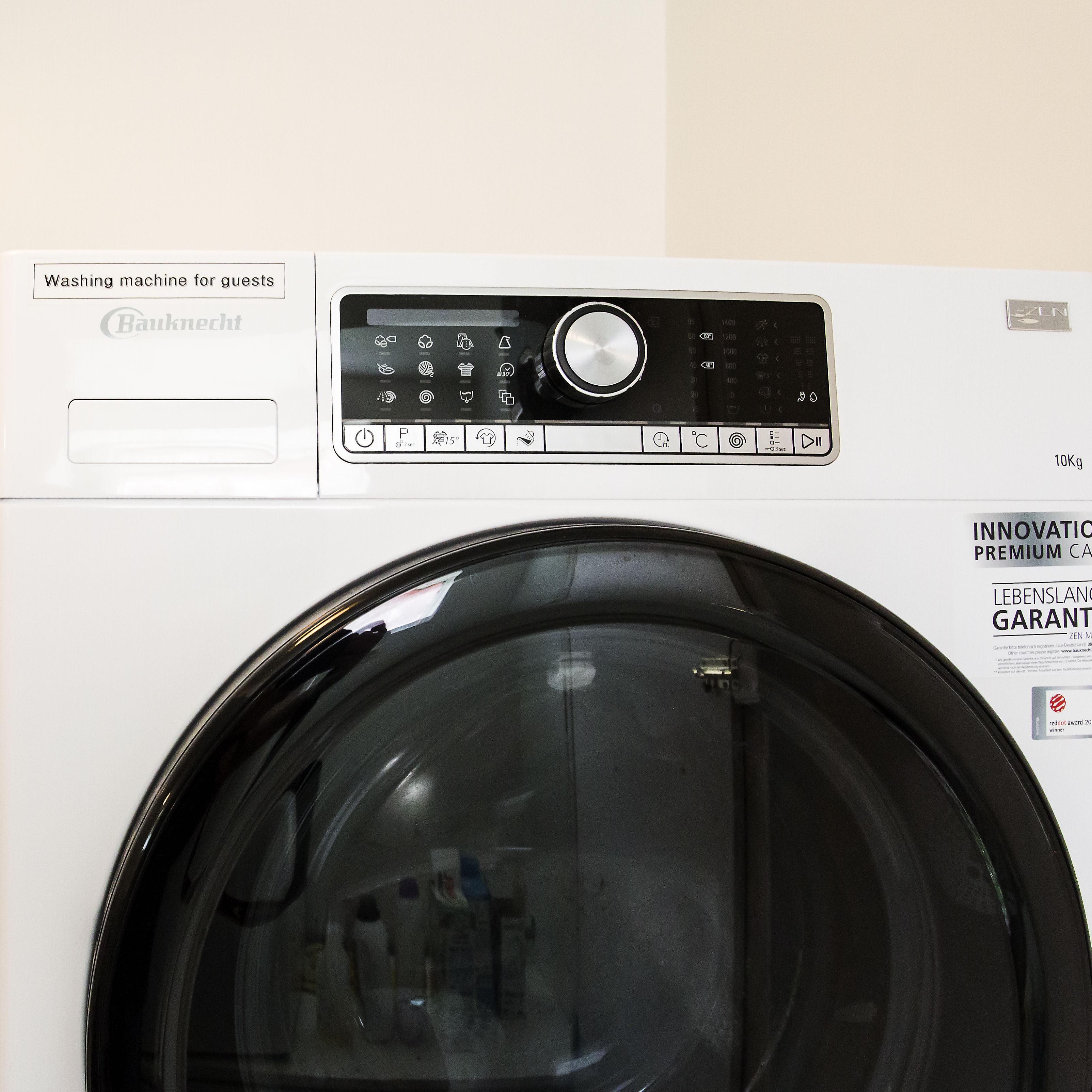 A front view of a Bauknecht washing machine with a control panel, a 10kg capacity label, and a red dot award sticker.