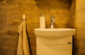 A bathroom with a wooden wall, a white sink, and a toilet.