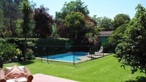 Un patio trasero con piscina, rodeado de una cerca y con mobiliario exterior.