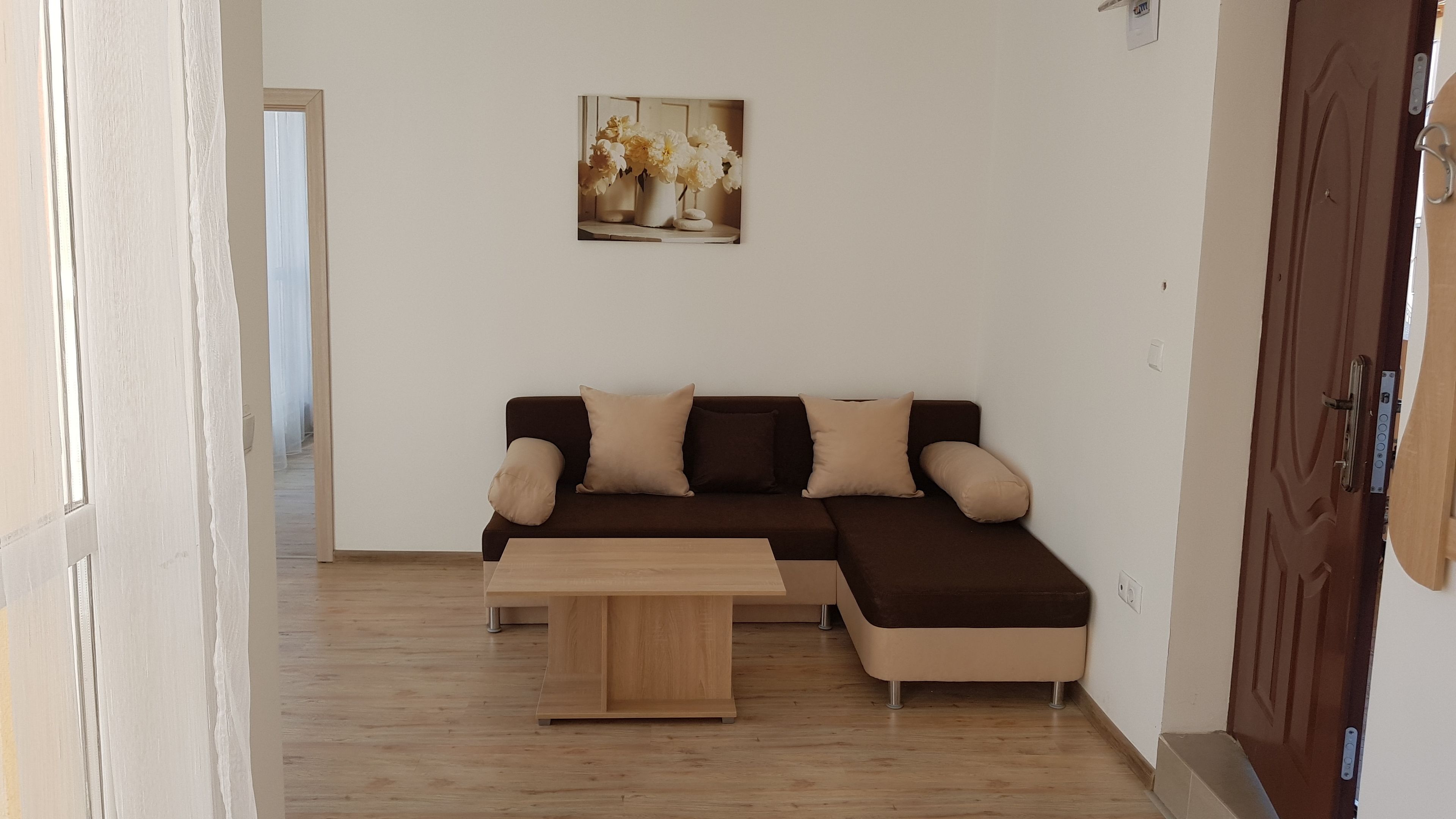 A living room with a brown sectional sofa, beige cushions, a wooden coffee table, and a framed picture on the wall.
